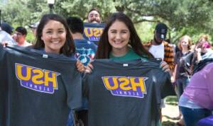 HSU graduates holding up tee shirts that read "HSU 校友"